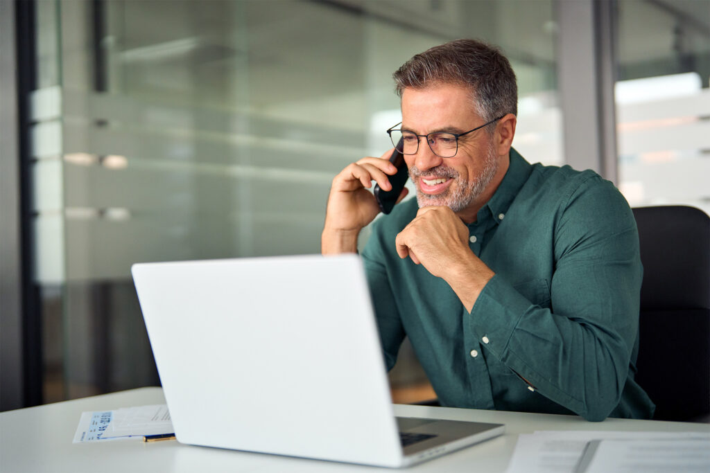 Middle age man looking at a laptop during a phone call